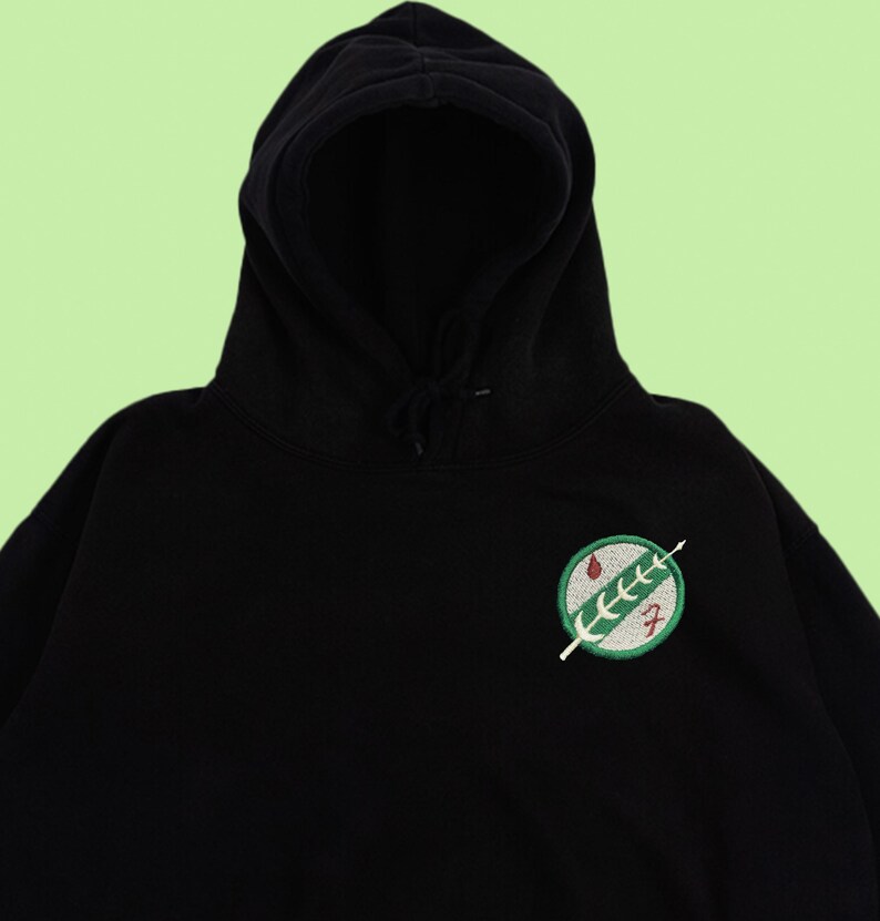 Puede incluir: Sudadera con capucha negra con un parche bordado verde y rojo del s&iacute;mbolo de la Alianza Rebelde de Star Wars.