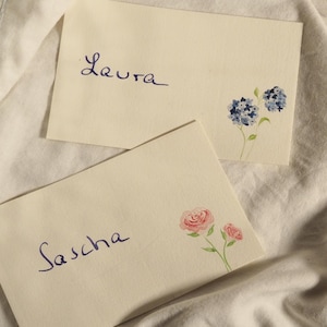 Tarjetas de mesa pintadas a mano con motivos florales.