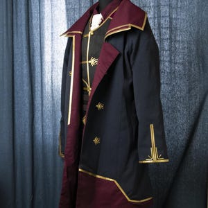 May include: A dark blue coat with a burgundy lining and gold trim. The coat has a high collar and a single button closure. The coat is decorated with gold embroidery.
