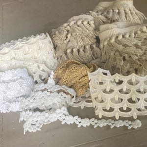 May include: Assortment of decorative trims in various styles and colors. Includes white scalloped lace, floral lace, and beige fringe trim. Ideal for sewing, crafting, and adding embellishments to fabric projects.