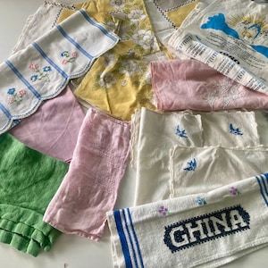 May include: A collection of vintage handkerchiefs in various colors and patterns. Includes white, pink, yellow, and green fabrics. Some feature floral embroidery, blue stripes, and the word "CHINA" in a navy blue design.