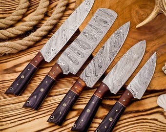 May include: Set of six kitchen knives with black and brown handles. The blades are made of Damascus steel and have a wavy pattern.