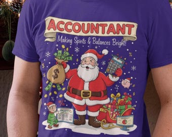 May include: A purple t-shirt with a festive design featuring Santa Claus holding a calculator and a bag of money. The text on the shirt reads "ACCOUNTANT Making Spirits & Balances Bright!" The design includes an elf, gifts, and snowflakes.