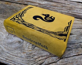 May include: A yellow book with a black squirrel illustration and the text "Squirrelfolk" on the cover.