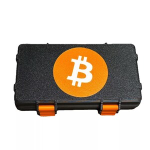 May include: Black rectangular storage case with an orange latch and a large orange circle with a white Bitcoin symbol in the center.