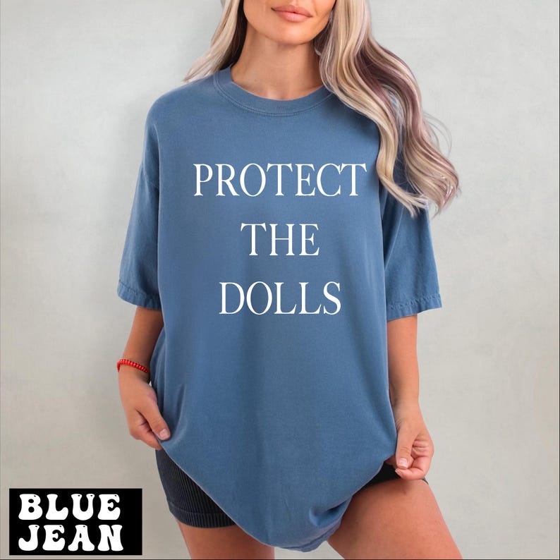 a woman wearing a blue shirt that says protect the dolls