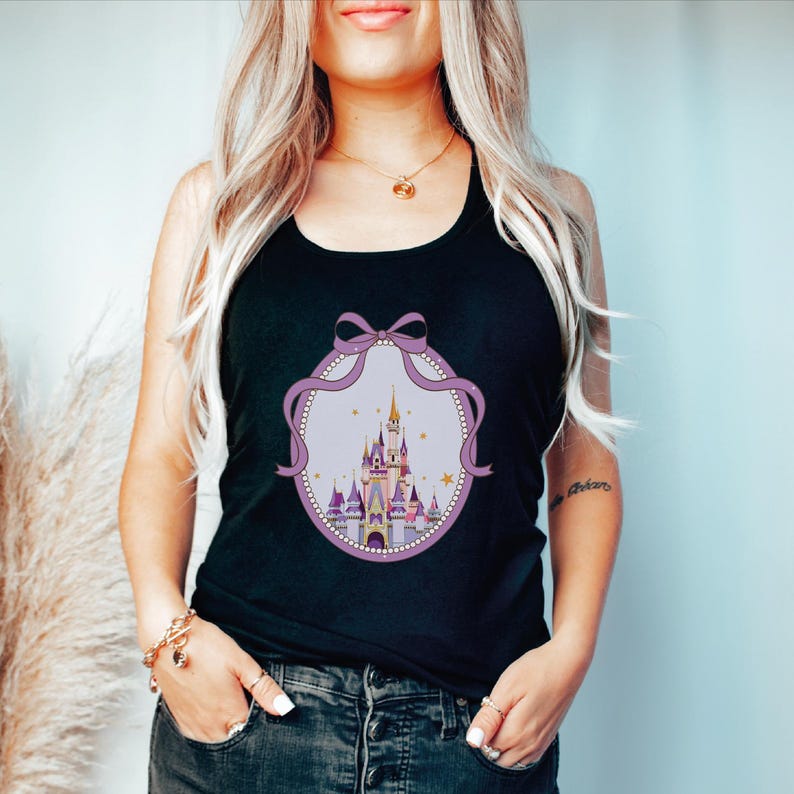 A woman with long blonde hair wearing a black tank top with a castle graphic on it.