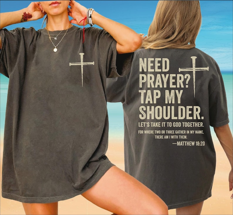 a person wearing a gray t-shirt with a Bible verse printed on the back.