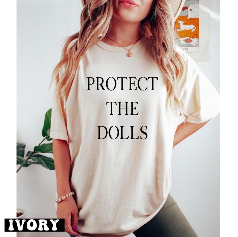 a woman wearing a t - shirt that says protect the dolls