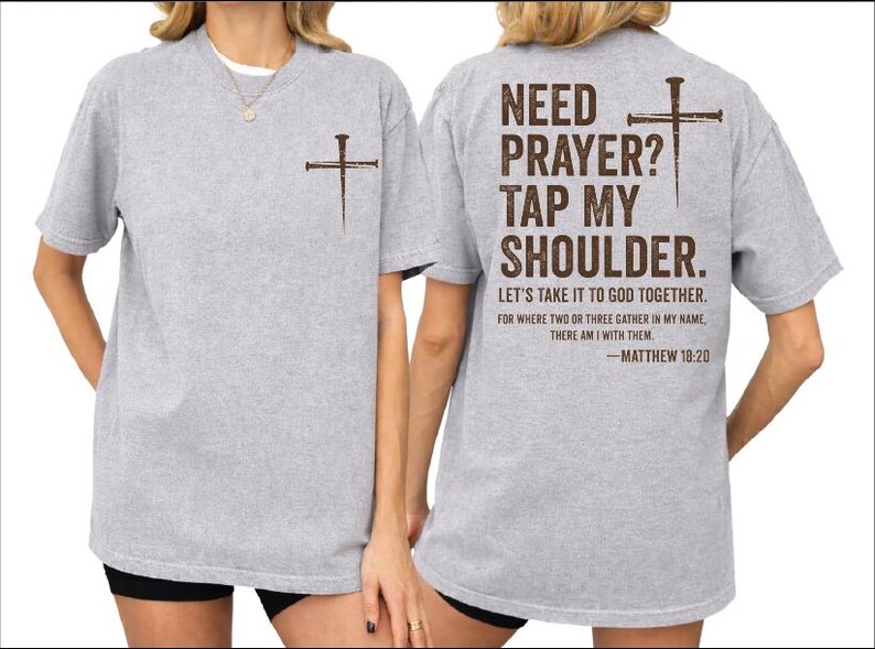 two gray t-shirts with a Bible verse printed on the back. The text on the back of the shirts reads "NEED PRAYER? TAP MY SHoulder. LET'S TAKE IT TO GOD TOGETHER. FOR WHERE TWO THIRTS GATHER IN MY NAME, THERE IS WITH THEM - Matthew 18:20".