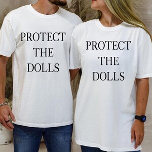 a man and woman wearing matching t - shirts that say protect the dolls