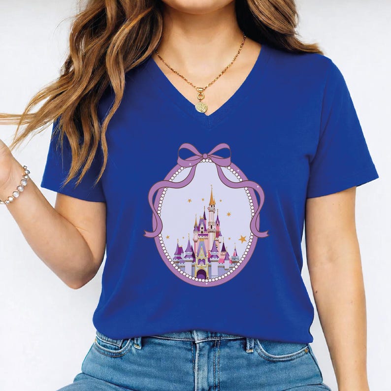 A woman wearing a blue t-shirt with a castle graphic and a pink ribbon design.