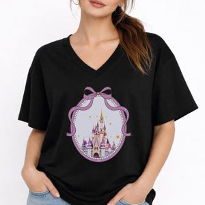 A woman wearing a black t-shirt with a graphic of a castle and a bow on it.
