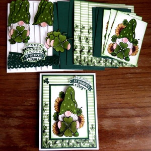 May include: A collection of St. Patrick's Day themed paper crafts. The image features a greeting card with a gnome holding a four-leaf clover, surrounded by sunflowers. Additional elements include cut-out gnomes, clovers, and cards with striped and floral patterns. The phrase "Happy St. Patrick's Day" is visible.