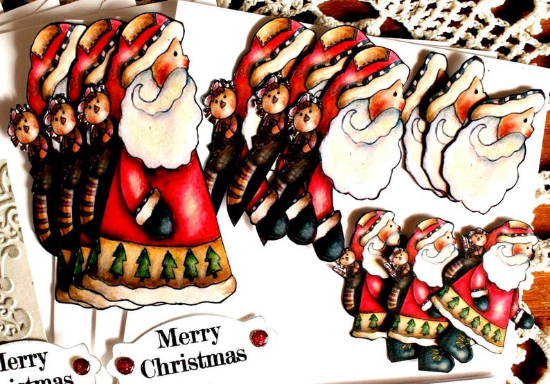 Op de afbeelding: Een verzameling uitgestanste papieren kerstmanfiguren met rode jassen met groene boompatronen, witte baarden en kleine dierenaccenten. Witte rechthoekige labels met de gedrukte tekst Merry Christmas zijn in de set inbegrepen.