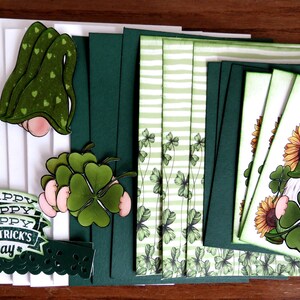 May include: A collection of St. Patrick's Day themed paper crafts. The image features green and white cards, gnome cutouts with shamrocks, and the text "Happy St. Patrick's Day". The gnomes have green hats and hold shamrocks.