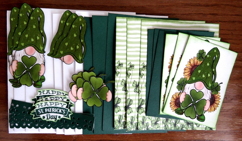 May include: A collection of St. Patrick's Day themed paper crafts. The image features green and white cards, gnome cutouts with shamrocks, and the text "Happy St. Patrick's Day". The gnomes have green hats and hold shamrocks.