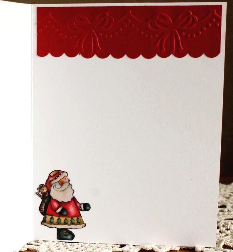 Op de afbeelding: Een witte wenskaart met een rode, in reli&euml;f aangebrachte rand aan de bovenzijde, voorzien van een geschulpte rand en een strikpatroon. In de linkerbenedenhoek staat een kleine, kleurrijke illustratie van de Kerstman in een rode jas.