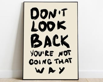 May include: Black and white typography print on a cream background. The text reads "Don't look back you're not going that way."