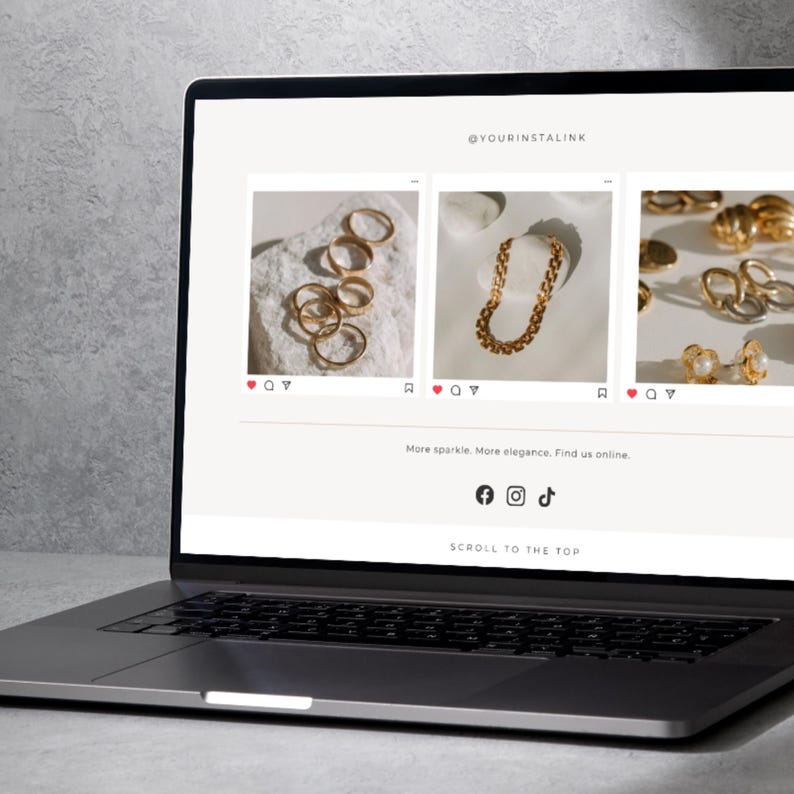 May include: A laptop displays an e-commerce website showcasing gold jewelry. The website features images of rings, a chain necklace, and earrings. The text "@YOURINSTALINK" is visible, along with social media icons and the phrase "SCROLL TO THE TOP."