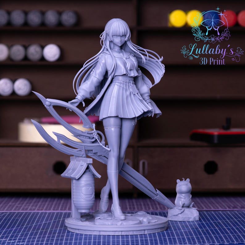 May include: A gray 3D-printed anime figurine of a female character with long hair, a pleated skirt, and a jacket. She holds a large weapon and stands on a circular base with a small animal figure. The figurine is detailed and stands in front of a blurred background.