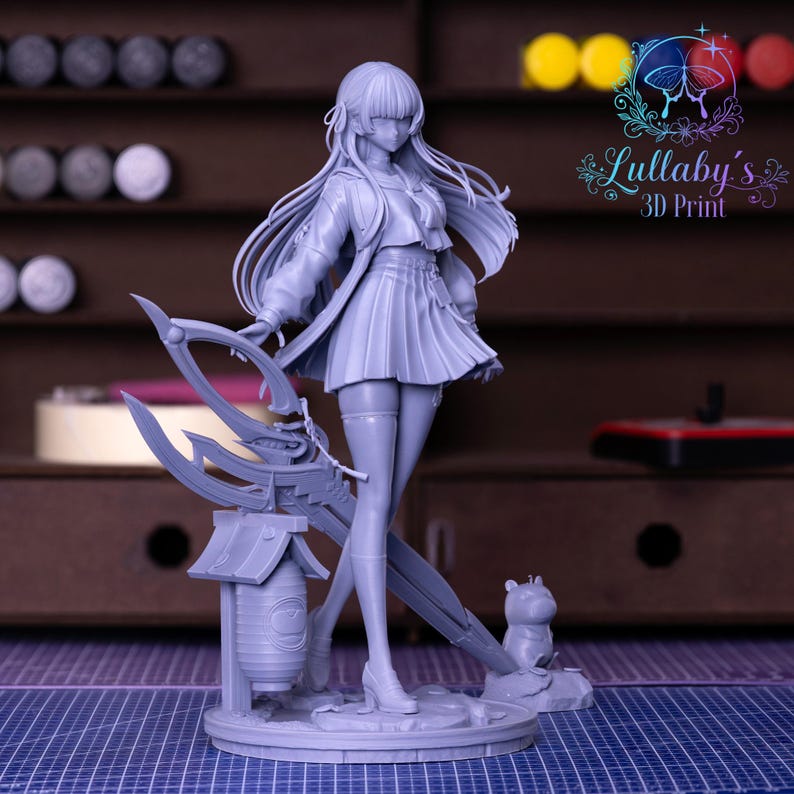 May include: A gray 3D-printed figurine of a female anime character. She wears a school uniform and holds a weapon. The figurine is standing on a base with a small animal figure. The logo "Lullaby's 3D Print" is visible.