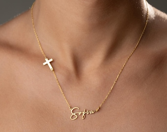 May include: A gold-colored necklace featuring a cross pendant and the name "Sofia" in cursive script. The necklace is worn around the neck and rests on a white garment.