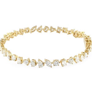 Könnte beinhalten: Ein goldenes Armband mit Diamanten in verschiedenen Formen, darunter oval, tropfenförmig und Smaragd. Die Diamanten sind eng gesetzt und erzeugen ein durchgehendes Funkeln. Das Armband befindet sich auf weißem Hintergrund.