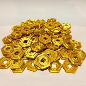 May include: A pile of gold-colored, hexagonal, plastic tokens with a square hole in the center.