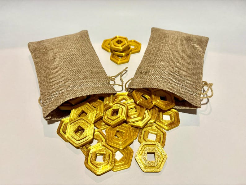 May include: Two burlap bags filled with gold-colored metal coins. The coins are shaped like octagons with a square hole in the center. The coins are spilling out of the bags onto a white surface.