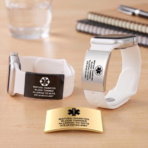 Puede incluir: Dos correas de reloj de silicona blanca con placas de alerta médica rectangulares en negro y plata, grabadas con un símbolo de estrella médica y el texto MAFUZA: DIABETES, BLOOD THINNER, ALLERGIC TO NUTS, ICE:(619)123-4567, además de una placa dorada.