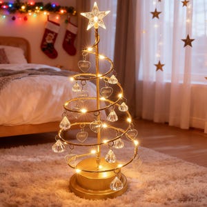 Puede incluir: Un árbol de Navidad dorado en espiral con una estrella en la parte superior y adornos en forma de corazón. El árbol está iluminado con luces blancas cálidas y se asienta sobre una base redonda. Adornos transparentes con forma de cristal cuelgan de la espiral.