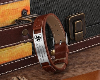 May include: A brown leather medical alert bracelet with a silver plate. The plate features a medical symbol and text: "Rita Smith Reus, NO BLOOD DRAW OR, ICE KRIS 559 438 5322". The bracelet has a buckle closure.