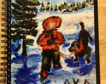 Zwarte spiraalgebonden notebook. Beeld van een Vrouw die haar Hond in de Sneeuw op de Voorzijde loopt. Afkomstig van een origineel kunstwerk.