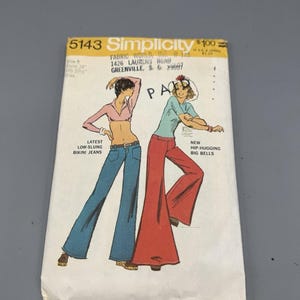 Peut inclure: Un paquet de patrons de couture Simplicity vintage, avec des illustrations de pantalons évasés et de hauts. Le paquet porte le numéro 5143 et contient le texte "Latest Low-Slung Bikini Jeans" et "New Hip-Hugging Big Bells". Le paquet est blanc avec une illustration colorée.