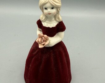 Statuetta vintage di una ragazza bionda con campana in velluto rosso e rosa rosa, 10 cm circa.