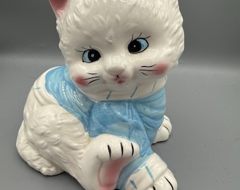 Salvadanaio vintage in ceramica a forma di gatto, 21,5 cm, bianco, blu, fiocco, occhi grandi, stile kitsch.
