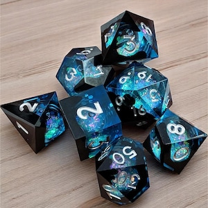May include: A set of polyhedral dice with a black and blue color scheme. The dice have a shimmering, galaxy-like interior and white numbering. The set includes various shapes, such as a d4, d6, d8, d10, d12, d20, and a percentile die.