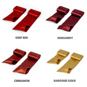 May include: Four sets of satin ribbon in deep red, burgundy, cinnamon, and baroque gold. Each set comprises two ribbons, with the colour names displayed below each set. The ribbons are rolled at one end and spread out at the other.