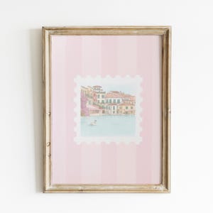 Pu&ograve; includere: Una stampa incorniciata con un'illustrazione ad acquerello di una scena sul lungomare europeo, simile a un francobollo. L'opera d'arte &egrave; ambientata su uno sfondo a righe rosa e incorniciata in una cornice di legno dorato. L'immagine raffigura edifici, acqua e un cigno.