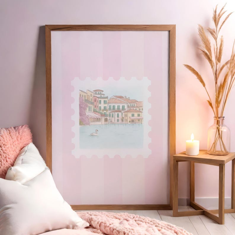Pu&ograve; includere: Una stampa incorniciata ad acquerello di una citt&agrave; lacustre europea con un cigno, su uno sfondo a righe rosa. La cornice in legno circonda l'opera d'arte, mostrando edifici, acqua e un cielo limpido. Il tema generale &egrave; l'arte decorativa.