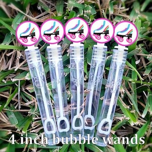 May include: Five clear bubble wands with pink and white roller skate toppers. Each wand is 4 inches long and filled with bubble solution. The wands are arranged on a bed of green grass. The text "4 inch bubble wands" is at the bottom.