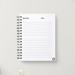 May include: A white spiral bound notebook with black lines and the words "My Notes" and "Date" at the top. The notebook has a black sun design at the bottom.
