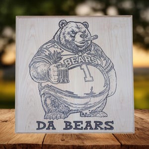 May include: A wooden sign featuring a detailed engraving of a bear wearing a football jersey with the word "BEARS" and the number 1. The bear is holding a mug and a cigar. The words "DA BEARS" are at the bottom.