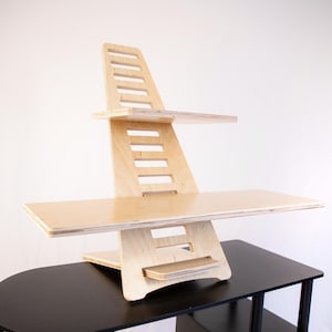 May include: A natural wood standing desk with two shelves. The desk is made of plywood and has a light wood finish. The desk is adjustable and can be raised or lowered to different heights.