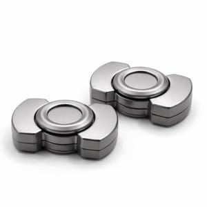 May include: Two silver metal fidget spinners. Each spinner has a circular centre and three curved arms. The spinners are displayed on a white background.