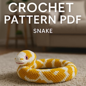Puede incluir: Un juguete de serpiente de ganchillo en posición enrollada, con un patrón amarillo y blanco. La cabeza de la serpiente es blanca con detalles en rosa para los ojos y la boca. El texto "CROCHET PATTERN PDF SNAKE" se muestra encima del juguete.
