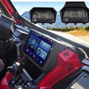 May include: A black dashboard camera mounted on the windshield of a red vehicle. The camera has a screen displaying the time 08:12 and a navigation map. The vehicle's interior is visible, including a black steering wheel and a black and silver radio.