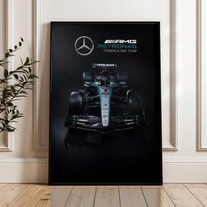 May include: A framed poster featuring a Formula One race car. The car is black with teal and silver accents, and the Mercedes-Benz logo is visible. The poster also includes the text "AMG Petronas Formula One Team."