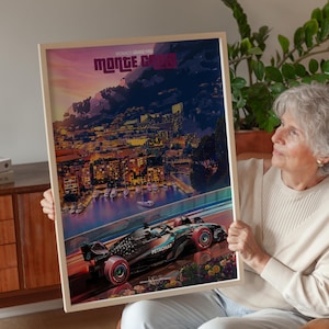 May include: A framed poster featuring a Formula 1 race car speeding along a track with the text "MONTE CARLO" and "MONACO GRAND PRIX". The background depicts a coastal city at dusk with illuminated buildings and boats.
